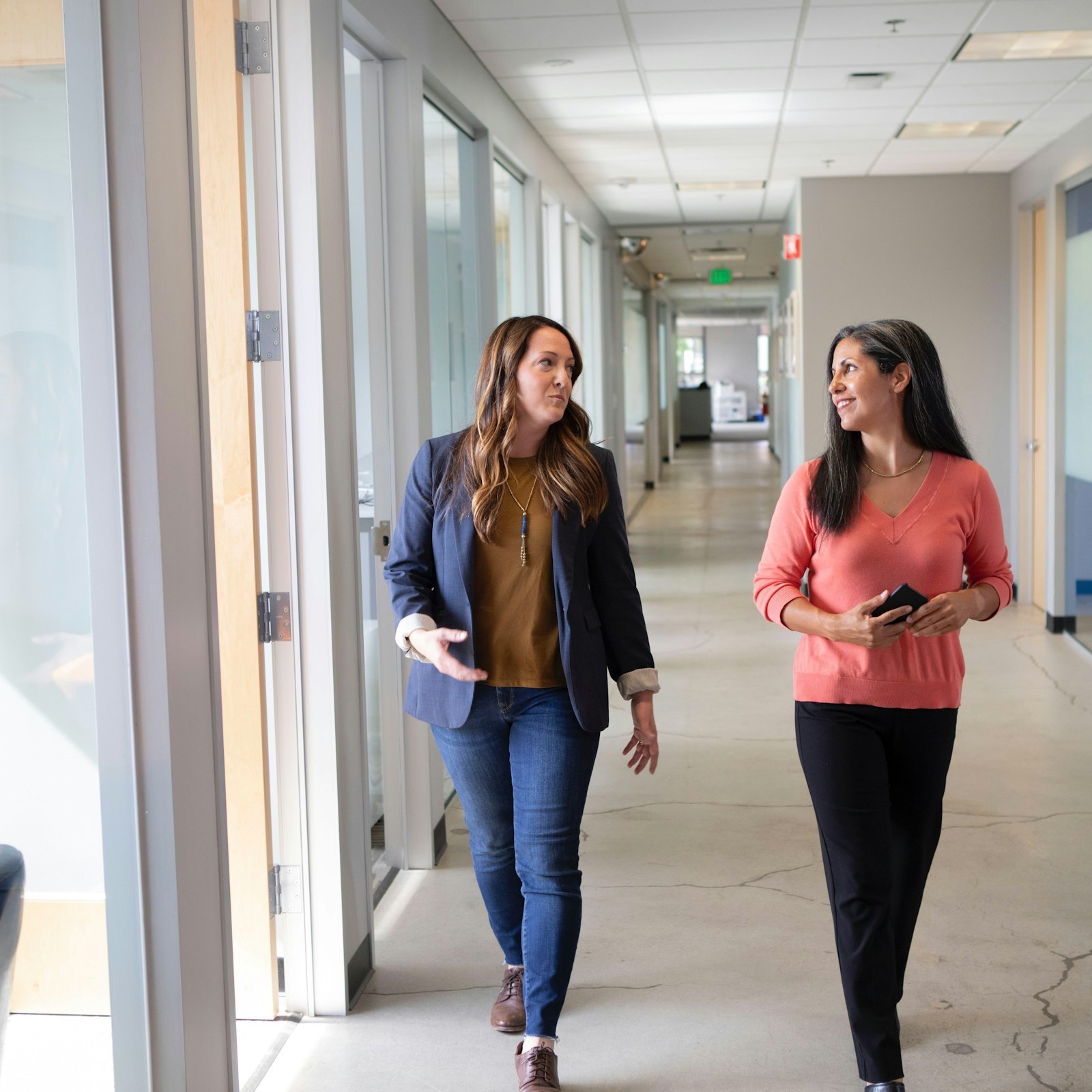 Two colleagues walking together down an office hallway, representing HansoAI walking alongside its clients
